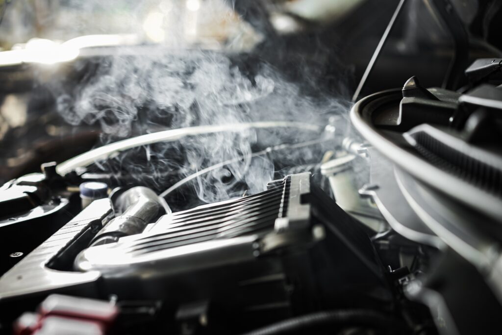 Motor de un coche sobrecalentado con vapor y medidor de temperatura