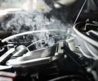 Motor de un coche sobrecalentado con vapor y medidor de temperatura